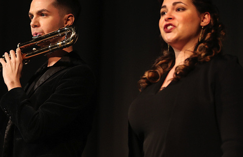 A musician playing a flute and a musician singing