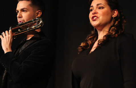 A musician playing a flute and a musician singing
